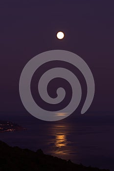 Full moon sea. The supermoon is orange in a purple sky over the ocean