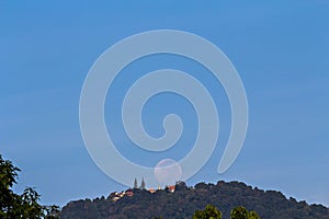 Full moon setting over Buddhist temple on mountain