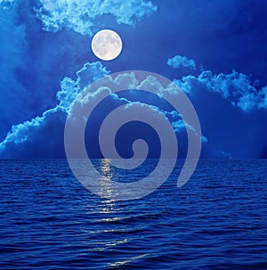 Full moon in sky with clouds over sea