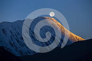 Full moon during a sunrise on the background of snow-capped in Himalayas mountains in Nepal