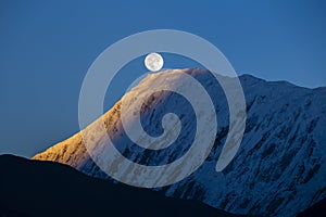 Full moon during a sunrise on the background of snow-capped in Himalayas mountains in Nepal