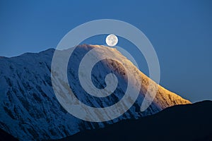 Full moon during a sunrise on the background of snow-capped in Himalayas mountains in Nepal