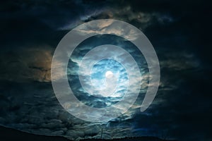 Full moon or supermoon in night blue sky with clouds, dramatic mysterious atmosphere photo