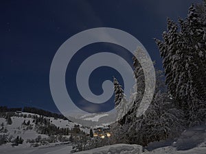 Full moon winter night fairytale, mountains and a village in the distance