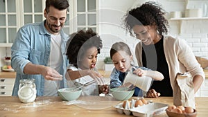 Full multi ethnic family cooking pancakes together in modern kitchen