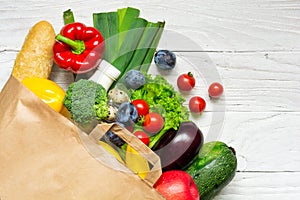 Full paper bag of different health food on white wooden background