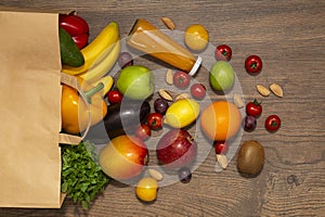 Full paper bag of different health food on wooden background, close up. Grocery shopping concept.