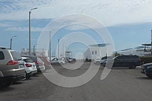 Almost full parking lot with a variety of cars on a condominium with a beautiful sky