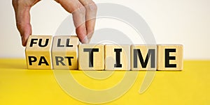 Full or part time. Hand is turning cubes and changes the word `full-time` to `part-time` or vice versa. Beautiful yellow table