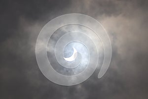 Full and partial Solar Eclipse seen in the cloudy sky.