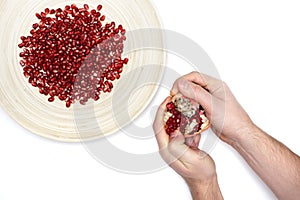 Full plate of peeled pomegranate seeds and a man de-seeding gran photo