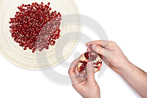 Full plate of peeled pomegranate seeds and a man de-seeding gran