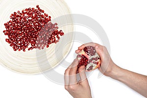 Full plate of peeled pomegranate seeds and a man de-seeding gran