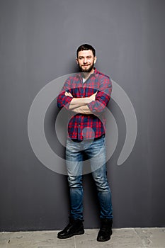 Full Portrait of handsome young man in casual shirt keeping arms crossed and smiling