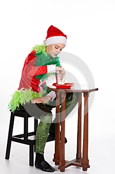 Full portrait of young girl wearing red santa clause hat dipping biscuit with concentration