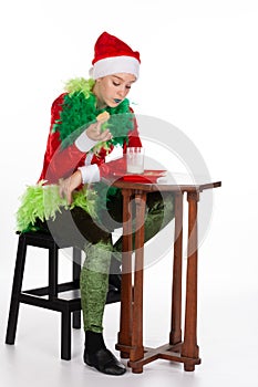 Full portrait of young girl wearing red santa clause hat dipping biscuit with concentration