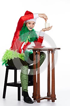 Full portrait of young girl wearing red santa clause hat perplexed with milk and biscuit