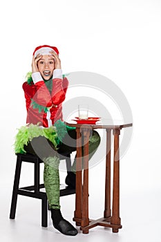 Full portrait of young girl wearing red santa clause hat shocked expression when eating biscuit