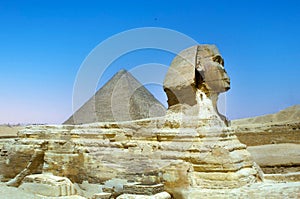 full profile of the Great Sphinx with the pyramid in the background in Giza