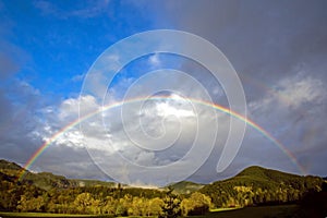 Full rainbow over forest hills