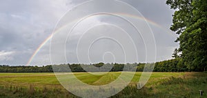 Full rainbow panorama against dark clouds