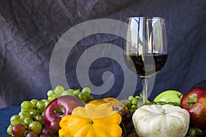 Full red wine glass and autumn and fall harvest, pumpkin, apple and grape