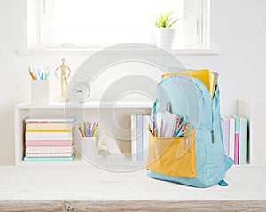 Full school backpack with different colorful stationery on wooden table