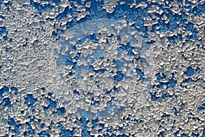 A full-screen texture of cracked white paint on a blue wall