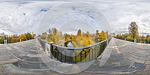 Full seamless spherical cube panorama 360 degrees angle view on pedestrian bridge across small river in autumn city park in