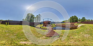 Full seamless spherical hdr 360 panorama near wooden pedestrian bridge over river near vacation home behind high fence in
