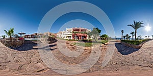 Full seamless spherical hdr 360 panorama view near of an two-story building  with landscaped area with palm trees in