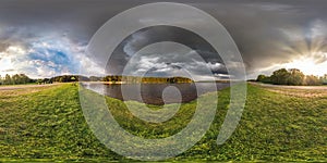 Full seamless spherical hdri panorama 360 degrees angle view on the shore of lake in evening before storm with black clouds in