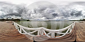 Full seamless spherical hdri panorama 360 degrees  angle view on wooden pier for ships on huge lake in gray rain sky in