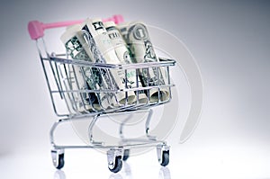 Full shopping trolley with dollar banknotes on a white background. Isolated. Concept of consumerism and money.