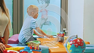 full shot of a blond little boy playing with a bike in the playroom, kids activities concept