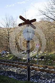 Full shot of an old stop sign beside a railroad with dried leafless tress in the background