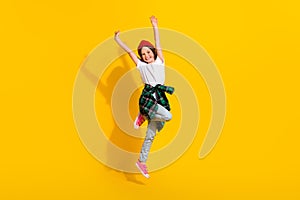 Full size photo of adorable schoolgirl raise hands jumping up wear trendy white outfit isolated on yellow color