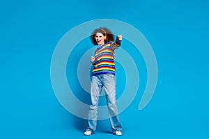 Full size photo of attractive young woman music earphones fight fist wear trendy rainbow print clothes isolated on blue