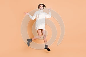 Full size photo of charming happy young woman wave hello jump up air isolated on beige color background