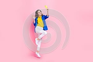 Full size photo of cheerful excited girl jumping hold telephone take selfie arm waving isolated on pink color background