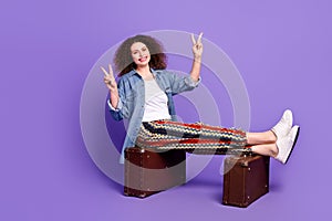 Full size photo of cool nice girl sit valise show v-sign wear denim shirt isolated on violet color background