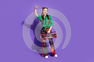 Full size photo of cool nice woman dressed green shirt print trousers hold boombox raising palm isolated on purple color