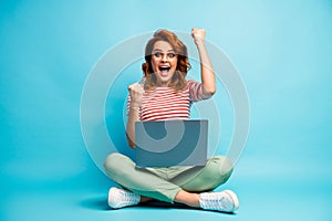 Full size photo of crazy cool smart woman sit legs crossed work computer finish her project scream yeah raise fists wear