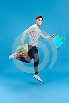 Full size photo of crazy handsome guy hurry rush hold packages jump isolated on blue color background
