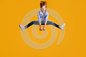 Full size photo of crazy redhead guy jumping high spreading legs sides rejoicing having best free time wear casual