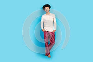Full size photo of cute young guy posing hands pockets shopping wear trendy white pajama outfit isolated on blue color