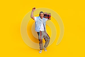 Full size photo of eccentric man dressed denim vest hold retro boombox raising palm up isolated on vibrant yellow color