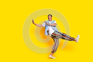 Full size photo of ecstatic man dressed denim vest stretching hands to object in empty space isolated on vibrant yellow