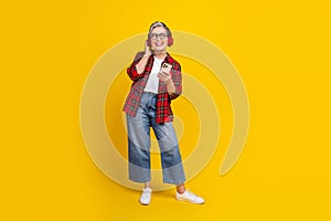 Full size photo of excited grandmother hand touch headphones hold smart phone empty space isolated on yellow color