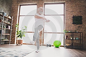 Full size photo of focused concentrated mature man warming up stretching legs doing cardio exercising at home house